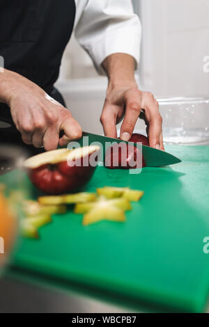 Photo recadrée d'un beau jeune cuisinier chef à la cuisine la cuisson à l'intérieur. Banque D'Images