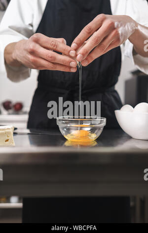 Photo recadrée d'un beau jeune cuisinier chef à la cuisine la cuisson à l'intérieur. Banque D'Images