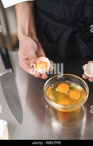 Photo recadrée d'un beau jeune cuisinier chef à la cuisine la cuisson à l'intérieur. Banque D'Images