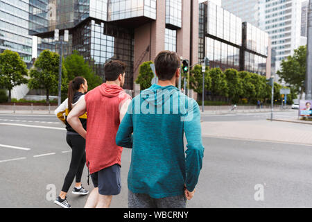 Photo de l'arrière de l'athletic young people wearing sportswear faisant d'entraînement et running on city street Banque D'Images