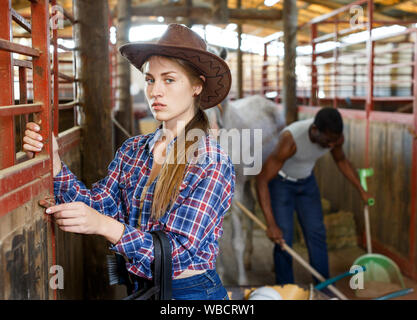 Portrait de jeune fille travailleuse agricole debout à horse stable Banque D'Images