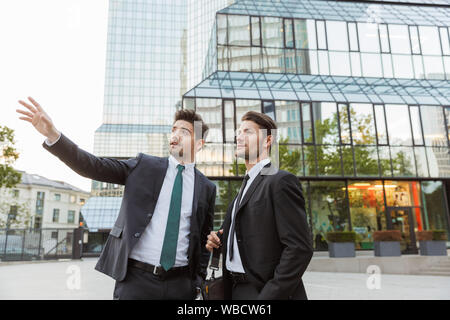 Deux beaux jeunes hommes d'assurance convient de porter à l'extérieur à l'article les rues de la ville, discuter de nouveau projet, dirigés à l'écart Banque D'Images