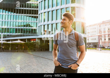 Beau jeune homme habillé de désinvolture passer du temps à l'extérieur de la ville, sac à dos de transport Banque D'Images