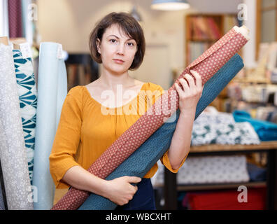 Portrait of smiling saleswoman travaillant en tissu boutique, organiser les rouleaux de tissu Banque D'Images