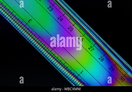 Image de polarisation croisée une règle indiquant les motifs colorés dans le plastique du stress Banque D'Images