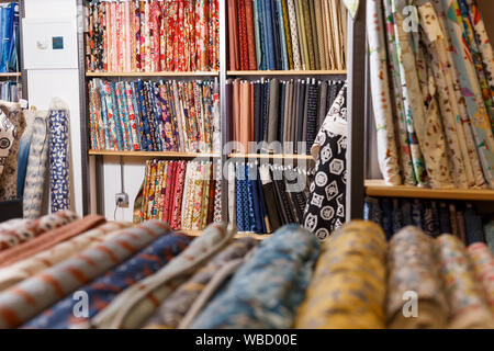 Avis de rouleaux de tissu de différentes couleurs et de motifs sur des étagères en tissu boutique Banque D'Images