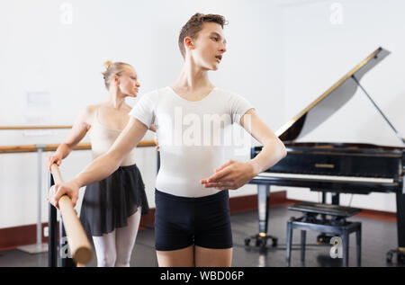 Chorégraphe femme et jeune homme de faire les exercices à la barre de ballet dans le hall avec miroir Banque D'Images