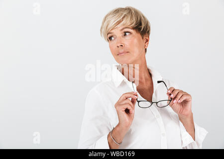 Portrait de femme adulte réussie holding eyeglasses et à côté isolated over white background en studio Banque D'Images