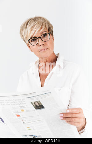 Portrait de concentré hot woman wearing eyeglasses reading newspaper isolé sur fond blanc en studio Banque D'Images