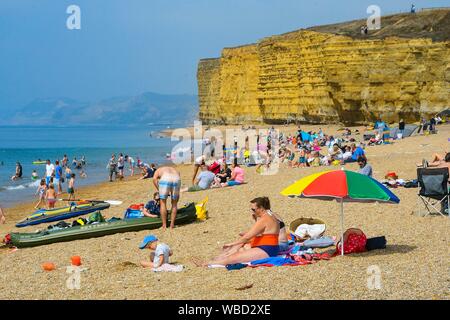 Burton Bradstock, Dorset, UK. 26 août 2019. Météo britannique. Les baigneurs et les vacanciers affluent à la plage à Burton Bradstock à Dorset pour un jour de températures chaudes et soleil voilé sur bank holiday lundi après un début de matinée brumeuse. Crédit photo : Graham Hunt/Alamy Live News Banque D'Images