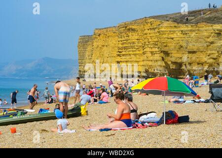 Burton Bradstock, Dorset, UK. 26 août 2019. Météo britannique. Les baigneurs et les vacanciers affluent à la plage à Burton Bradstock à Dorset pour un jour de températures chaudes et soleil voilé sur bank holiday lundi après un début de matinée brumeuse. Crédit photo : Graham Hunt/Alamy Live News Banque D'Images