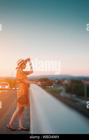 Jeune femme en robe orange sur le pont Banque D'Images