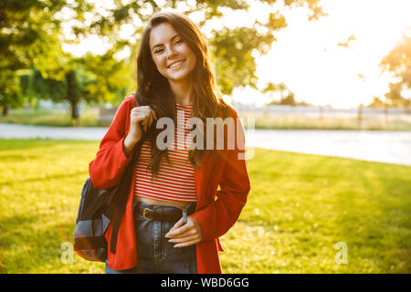 Droit de nice girl student wearing red jacket smiling at camera et en vous promenant dans Green Park Banque D'Images