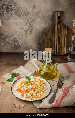 Pilaf de boulgour au poulet dans une assiette et un bol de salade de chou sur un béton fond brun Banque D'Images