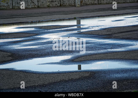 Sky reflète dans une flaque d'eau sur la chaussée, lever tôt le matin Banque D'Images