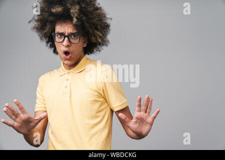 Photo de crispé caucasian man with afro hairstyle gesturing stop et montrant ses paumes sur fond gris isolé Banque D'Images