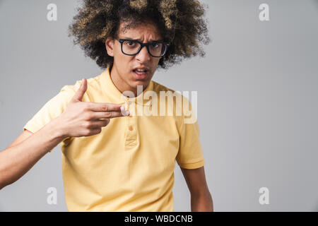 Photo de mad man avec coiffure afro froncer et montrant des armes à feu au doigt geste isolé sur fond gris Banque D'Images