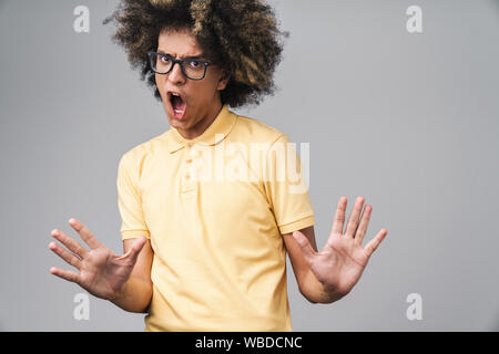 Photo de malheureux caucasian man with afro hairstyle gesturing stop et montrant ses paumes sur fond gris isolé Banque D'Images