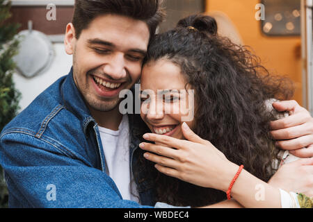 Gros plan Portrait de beau couple homme et femme en riant avec les yeux fermés tout en serrant près de maison sur roues à l'extérieur Banque D'Images