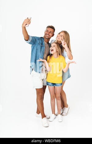 Longueur complète photo de femme joyeuse et l'homme avec little girl smiling on cellphone selfies tout en tenant plus isolé sur fond blanc Banque D'Images