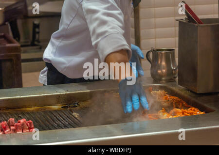 Le chef vous mijote de langoustes et de côtes sur smoky cuisinière électrique Banque D'Images