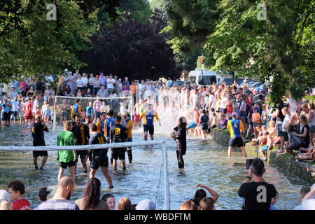 Bourton-on-the-water, Gloucestershire, Royaume-Uni. 26 août 2019. Deux équipes de football à cinq un jouer les uns les autres dans la rivière Windrush dans la ville de Cotswold Bourton-on-the-l'eau. Les foules se rassemblent pour profiter du spectacle qui soulève des fonds pour des œuvres de bienfaisance football. La rivière n'est qu'à la cheville, mais la tradition est de cent ans. Crédit : Mr Standfast/Alamy Live News Banque D'Images