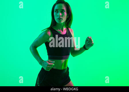 Image d'une jeune femme très sérieuse de sport bleu wall background avec néon lumières lumineuses d'exécution. Banque D'Images