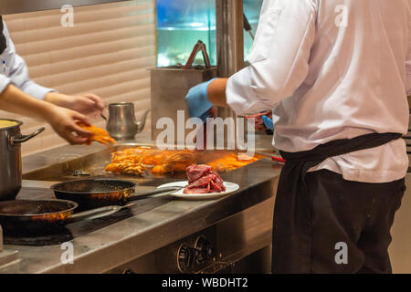 Le chef de la préparation et de la viande bovine en crevettes cuisine restaurant Banque D'Images