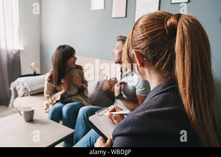 Photo de couple nerveux en colère contre l'homme et la femme d'avoir une conversation avec un psychologue sur séance de thérapie dans la chambre Banque D'Images