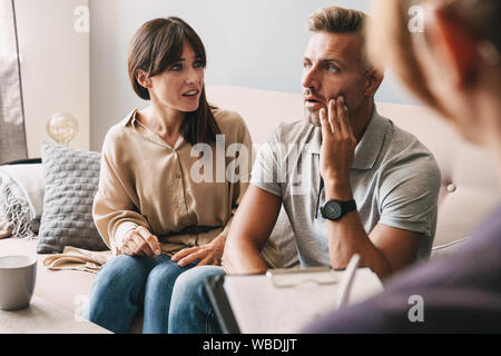 Photo de couple ennuyé malheureux l'homme et la femme d'avoir une conversation avec un psychologue sur séance de thérapie dans la chambre Banque D'Images