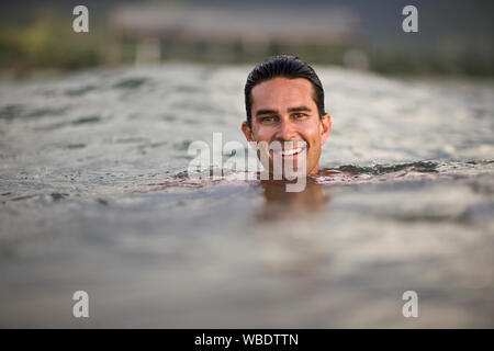 Homme nager dans la mer sourire alors qu'il pose pour un portrait. Banque D'Images