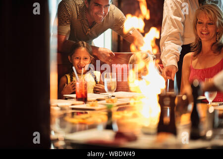 La famille à un restaurant japonais teppanyaki, regardant le feu chef la plaque. Banque D'Images