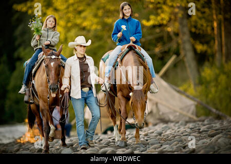 Deux jeunes filles portant des fleurs tout en étant mené à cheval. Banque D'Images