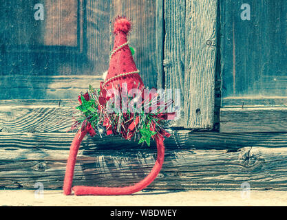 Fête de Noël hat contre vieille porte en bois. Célébration brillante rouge et vert diadem. Style rétro. Banque D'Images