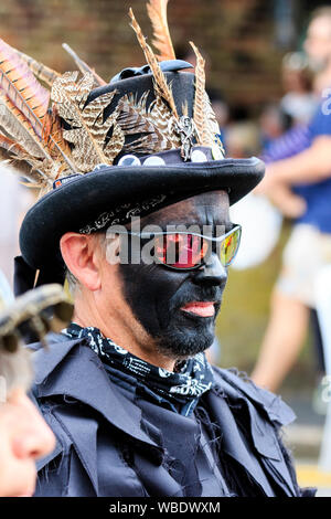 Folk Festival Ale et sandwich. Border morris danseur de la tête de loup du côté de Morris. Porter tout noir, lunettes de soleil et chapeau haut de forme, le visage noir. Banque D'Images