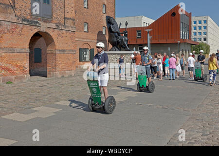 Touristes en segway visite guidée en passant par la sculpture noire de Mary Thomas devant l'ancien entrepôt ouest indien, devenu la collection de fonte royale. Copenhague Banque D'Images