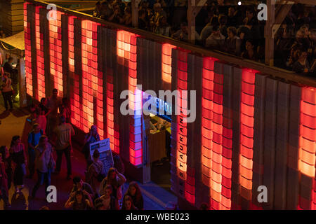 Stadtfest Brugg 24 août 2019. photographie de nuit. Mur en plastique lumineux rouge de Kubus Kolor avec des gens en haut et des gens qui marchent Banque D'Images