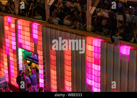 Stadtfest Brugg 24 août 2019. Photographie de rue. Rose et rouge en plastique lumineux mur de Kubus Kolor avec les gens sur le dessus Banque D'Images