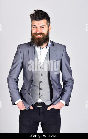 Homme barbu en costume sur fond gris. hipster en veste a confindent look. barbe et de soins de coiffure. businessman détient les mains dans la poche Banque D'Images