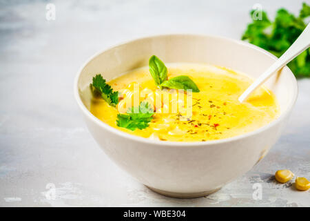 Soupe crème de maïs végétaliens dans bol blanc sur fond gris. Banque D'Images