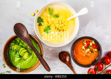 Trois différentes soupes crème de légumes dans des bols sur un fond gris. Le maïs, le concombre et le gazpacho de soupes. Banque D'Images