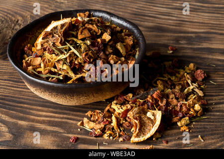Tas de fruits secs infusion de thé avec des oranges et des fraises mélangées avec les feuilles de thé et un assortiment de fines herbes dans un bol sur la table en bois avec fond sélectionnez Banque D'Images