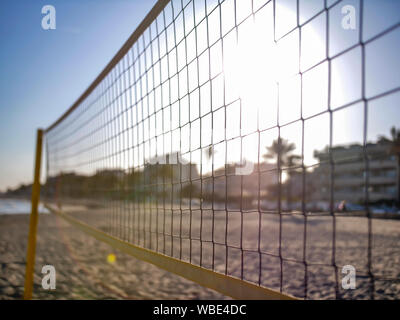 Filet de volley-ball jaune sur la plage, Coucher de soleil à travers le net Banque D'Images