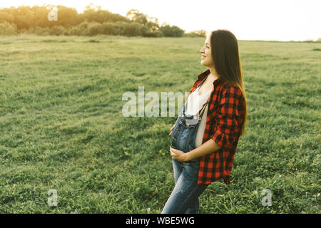 Brunette blanc femme enceinte en salopette denim Banque D'Images