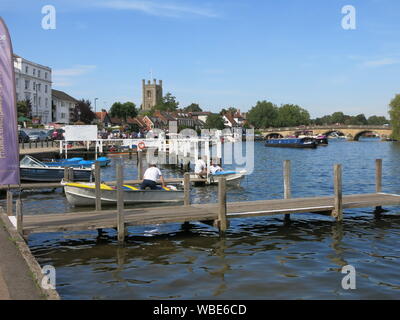 Vue de la promenade Riverside à Henley-on-Thames, sur une journée d'été avec un bon nombre de bateaux amarrés au Henley Moorings et le Henley Bridge en arrière-plan. Banque D'Images