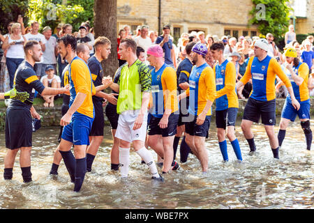 Match de football de bienfaisance a joué dans la rivière Windrush à Bourton-on-the-water, Cotswolds, Royaume-Uni. Match de football à river Bank Holiday août lundi. Banque D'Images