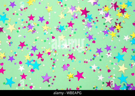 Aluminium coloré confettis étoiles clairsemée sur fond couleur menthe à la mode. Maison de vacances simple texture. Haut de la vue, télévision lay Banque D'Images