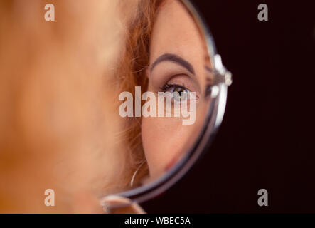 Femme, woman's eye reflétée dans un petit miroir rond. Vision and Ophthalmology concept Banque D'Images