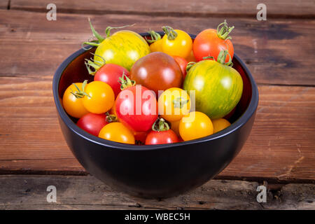 Mélanger les tomates fraîches de variété bol sur la planche en bois table rustique Banque D'Images