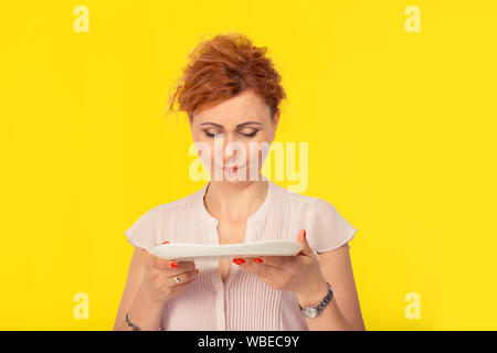 Malheureux woman holding ou à une plaque vide, isolé sur fond jaune plat. Concept de régime. Vous pouvez placer la nourriture que vous le souhaitez sur la plaque. Banque D'Images